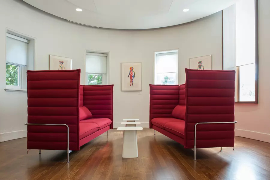 Two modern red love seats face each other in curved room